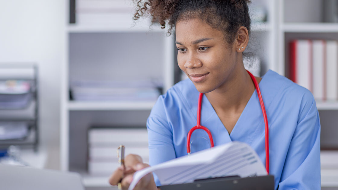 Nurse reviewing clinical documentation while entering patient notes in an EMR system
