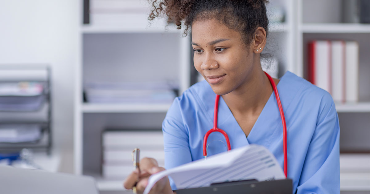 Nurse reviewing clinical documentation while entering patient notes in an EMR system